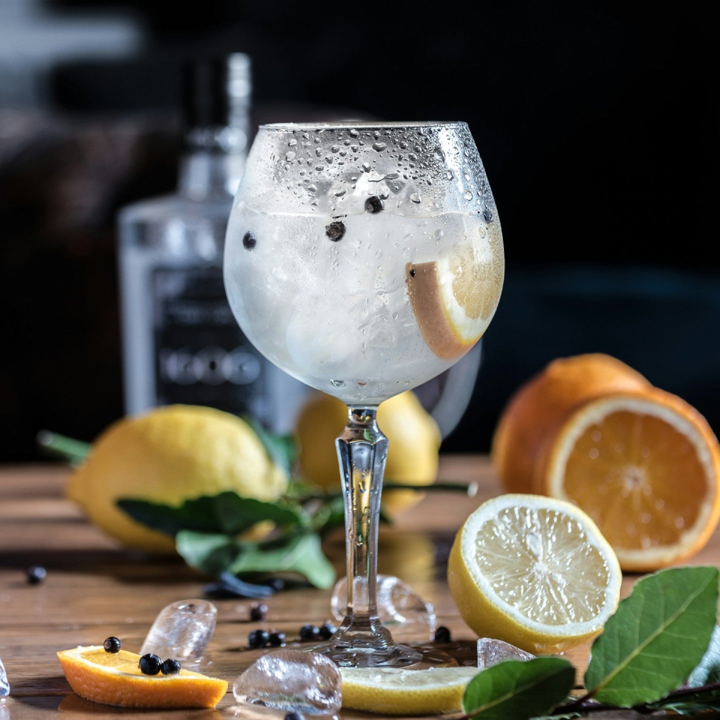 Gin and tonic cocktail with lemon and orange on a wooden surface