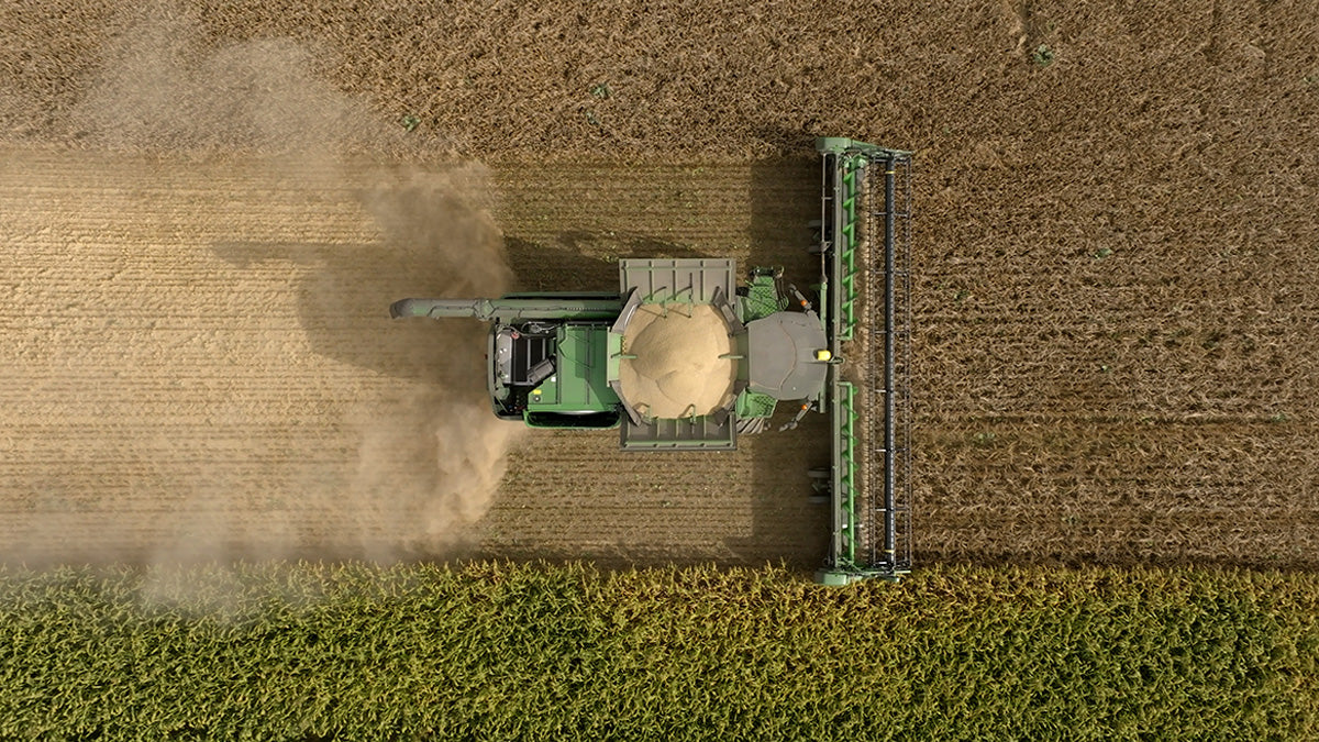 Aerial view of a combine harvesting grain in a vast field.